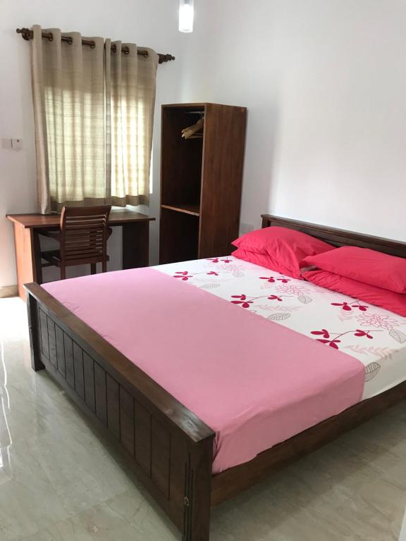 een slaapkamer met een groot bed en een roze deken bij Transit Studio Katunayake in Katunayaka