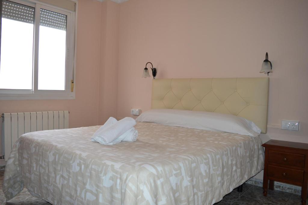 a bedroom with a bed with white sheets and a window at Hotel Doña Carmen in Ronda