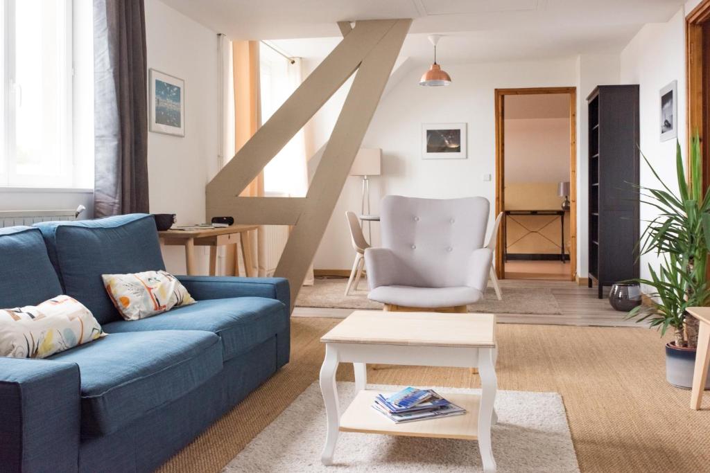 a living room with a blue couch and a table at Calme et lumière à proximité de la Vieille Ville de Boulogne sur mer in Boulogne-sur-Mer