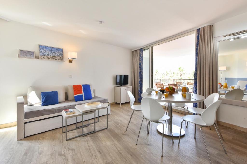a living room with a table and a couch at Résidence Pierre & Vacances Premium Port Prestige in Antibes