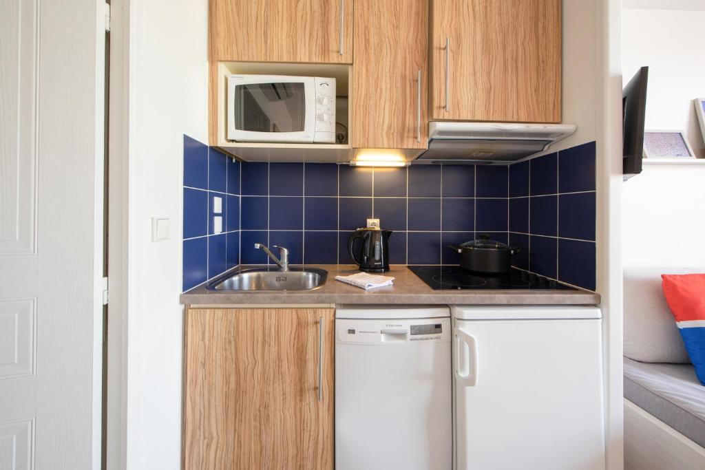 a small kitchen with a sink and a microwave at Résidence Pierre & Vacances Premium Port Prestige in Antibes