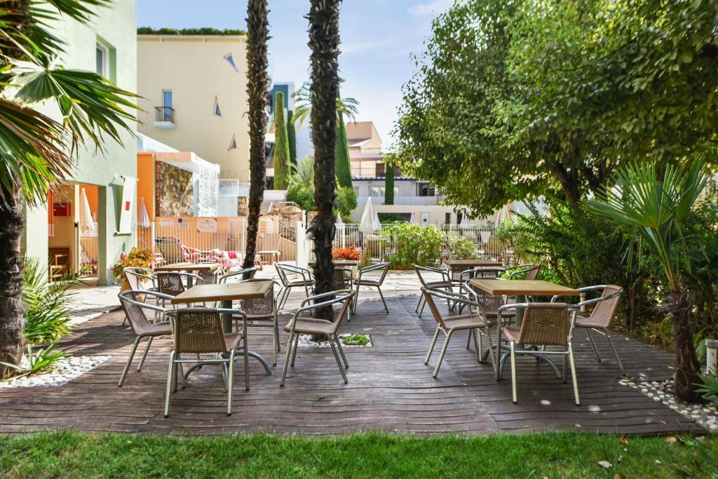 an outdoor patio with tables and chairs and trees at Résidence Pierre & Vacances Premium Port Prestige in Antibes