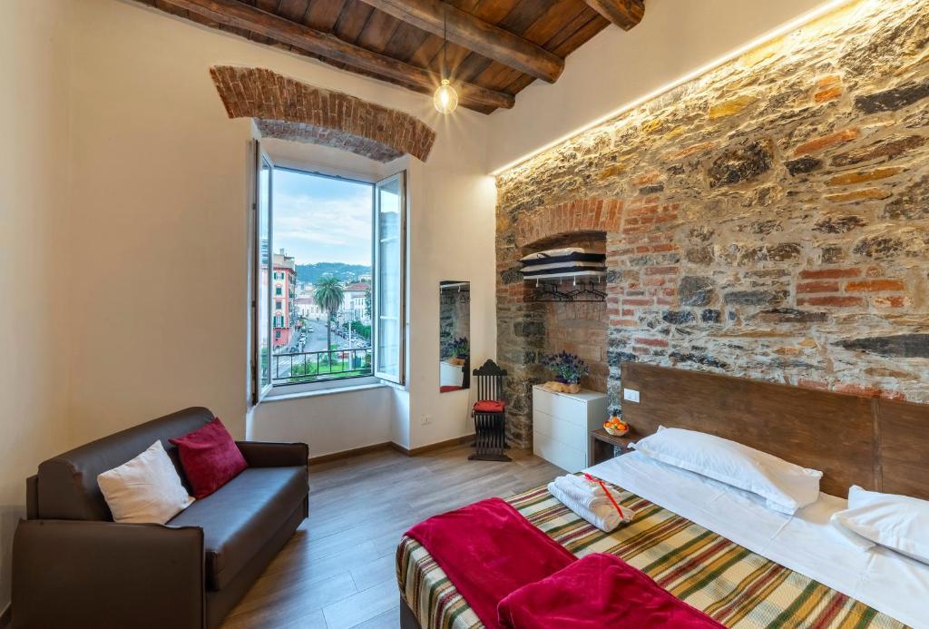 une chambre avec un mur de briques, un lit et un canapé dans l'établissement Affittacamere Superior del Golfo e delle 5 Terre, à La Spezia
