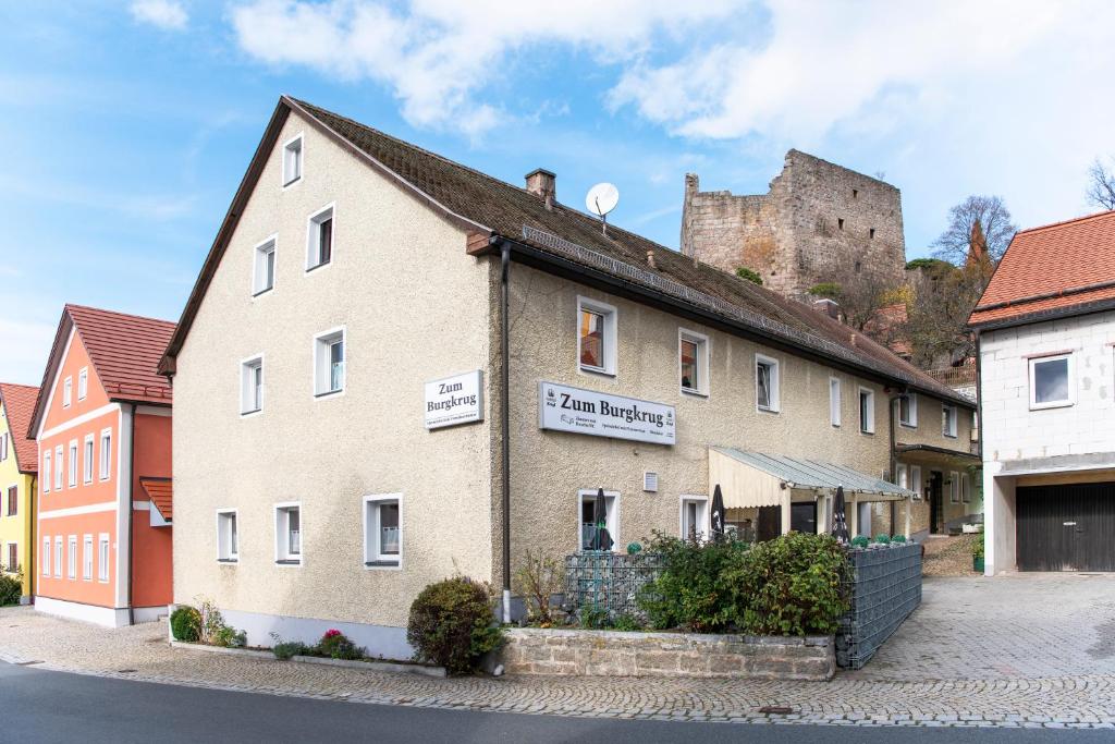 Gasthof Zum Burgkrug في Leuchtenberg: مبنى مع قلعة في الخلفية