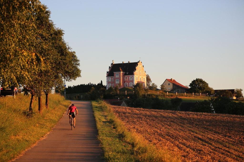 a person riding a bike down a path in front of a house at Hotel Schloss Freudental in Allensbach