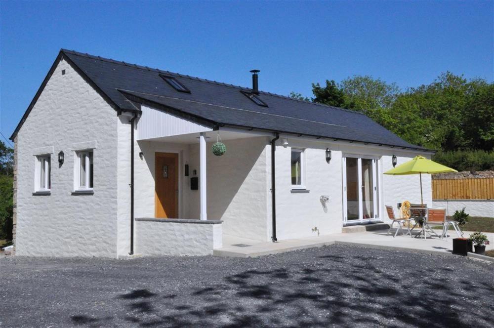 a white house with a patio and a yellow umbrella at Y Felin in Cardigan