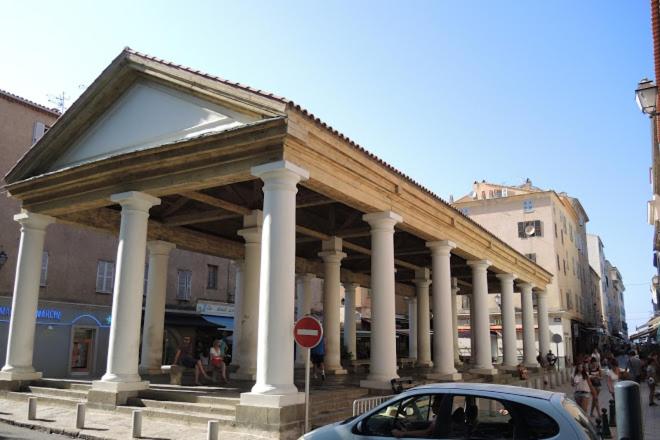 une voiture garée devant un immeuble avec colonnes dans l'établissement Appartement à Ile Rousse, à LʼÎle-Rousse