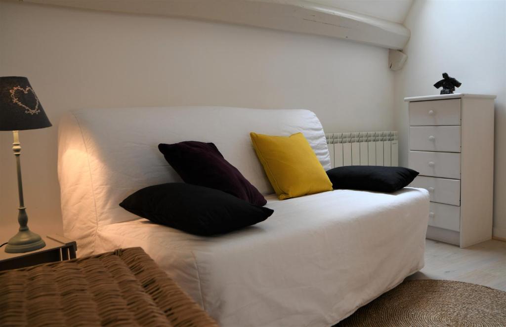 a white bed with four pillows on top of it at La Petite Maison d'à Côté in Saint-Aignan