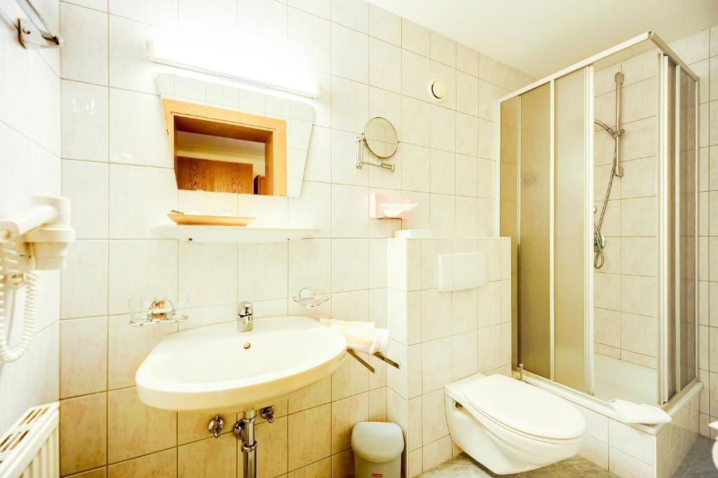 a white bathroom with a sink and a toilet at Hundehotel Riederhof in Ried im Oberinntal