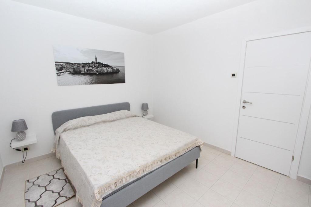 biała sypialnia z łóżkiem i zdjęciem na ścianie w obiekcie Apartment Stellina w Rovinj