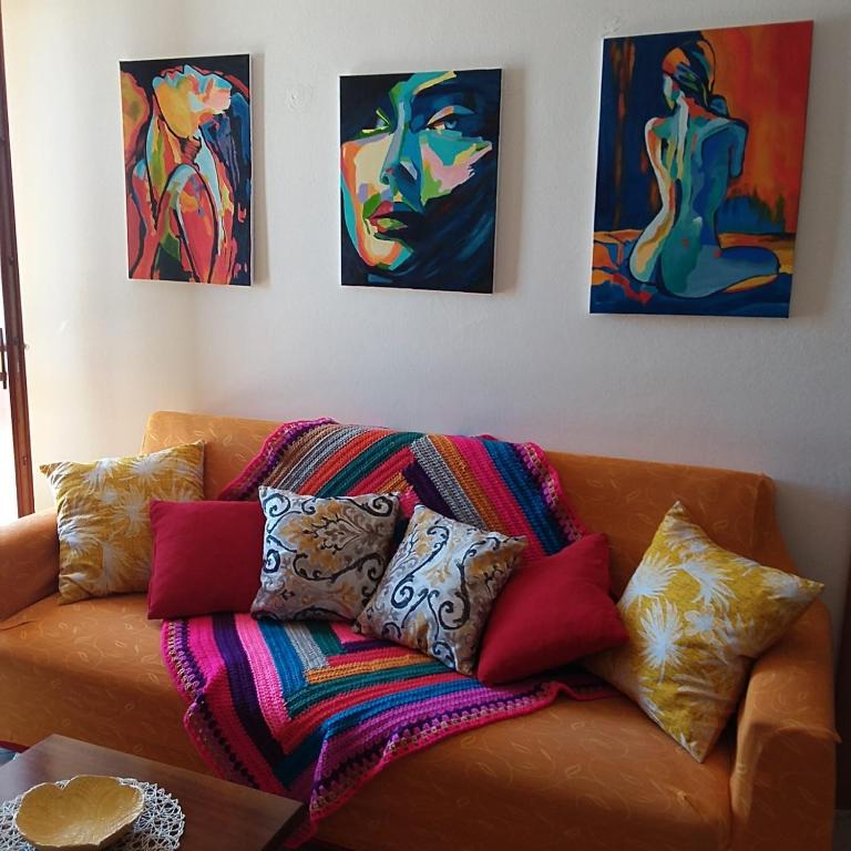 un divano con cuscini colorati e quadri alle pareti di Casa vacanze Antonella Pula a 750mt dal centro. a Pula