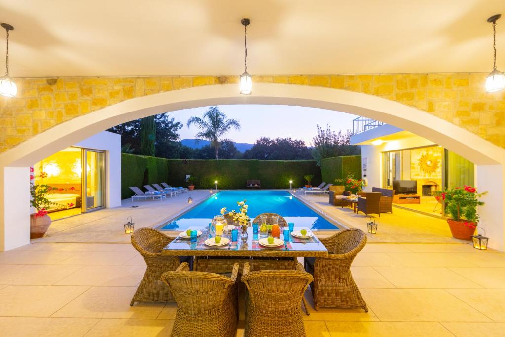 eine Terrasse mit einem Tisch und einem Pool in der Unterkunft Villa Zoe in Miliou