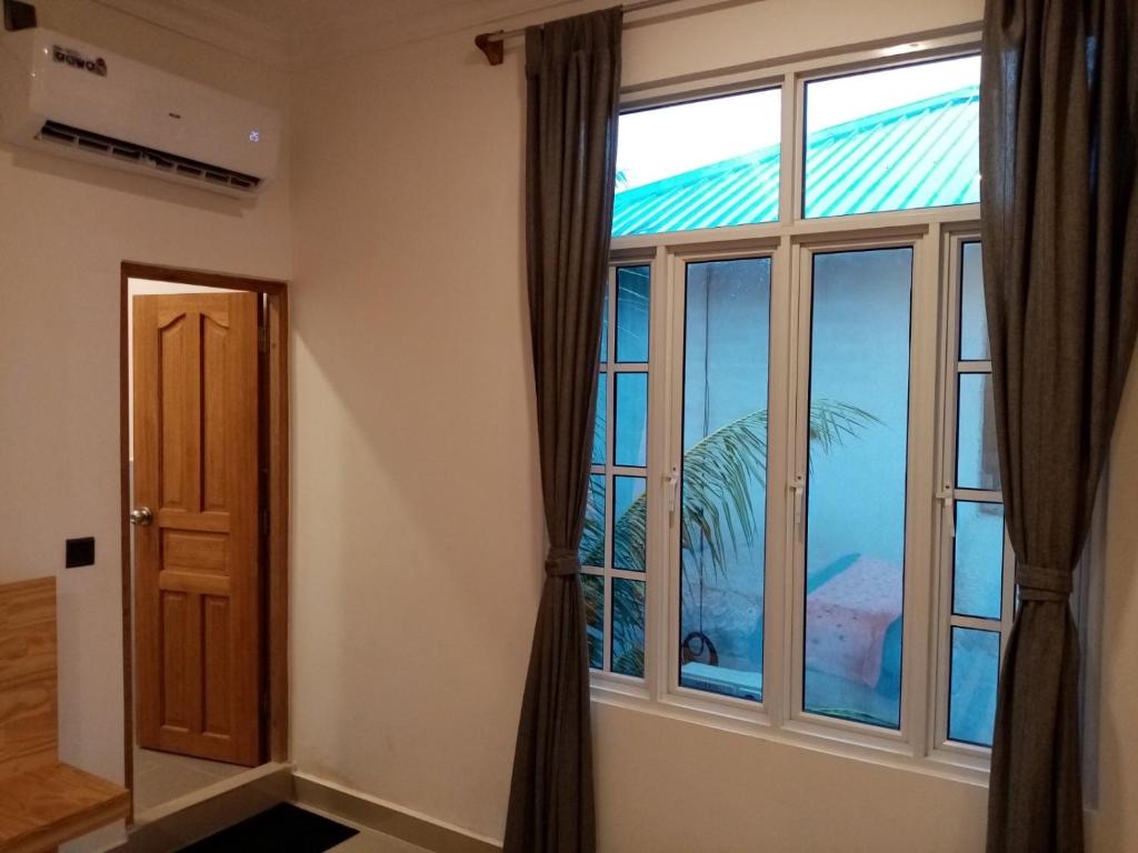 Dhonveli Inn, Bandidhoo في ميدهو: غرفة مع نافذة كبيرة وباب