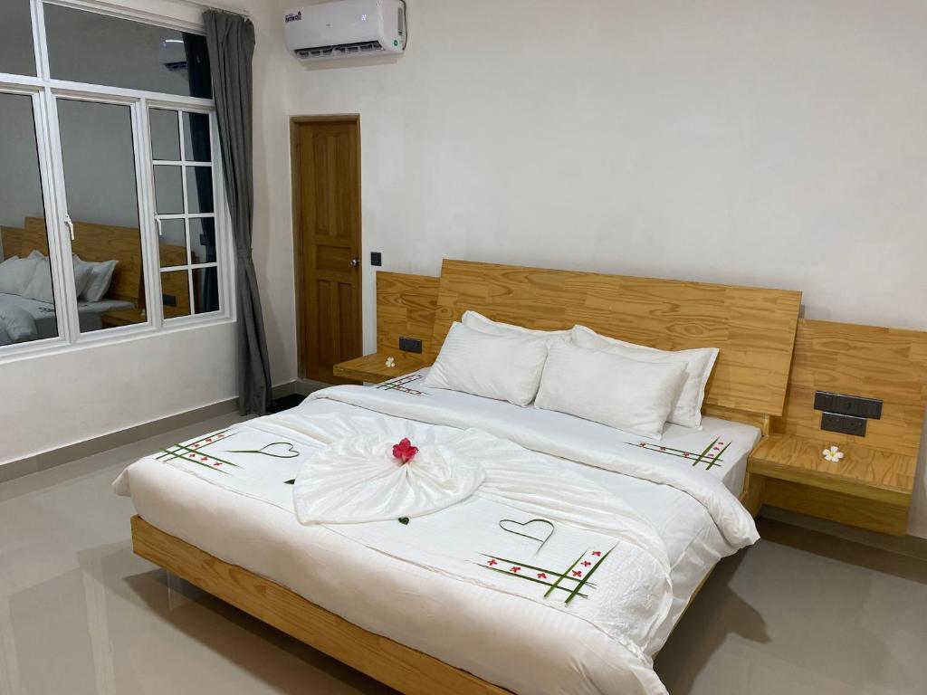 ein Schlafzimmer mit einem großen Bett mit einer Blume darauf in der Unterkunft Dhonveli Inn in Dhaalu Atoll