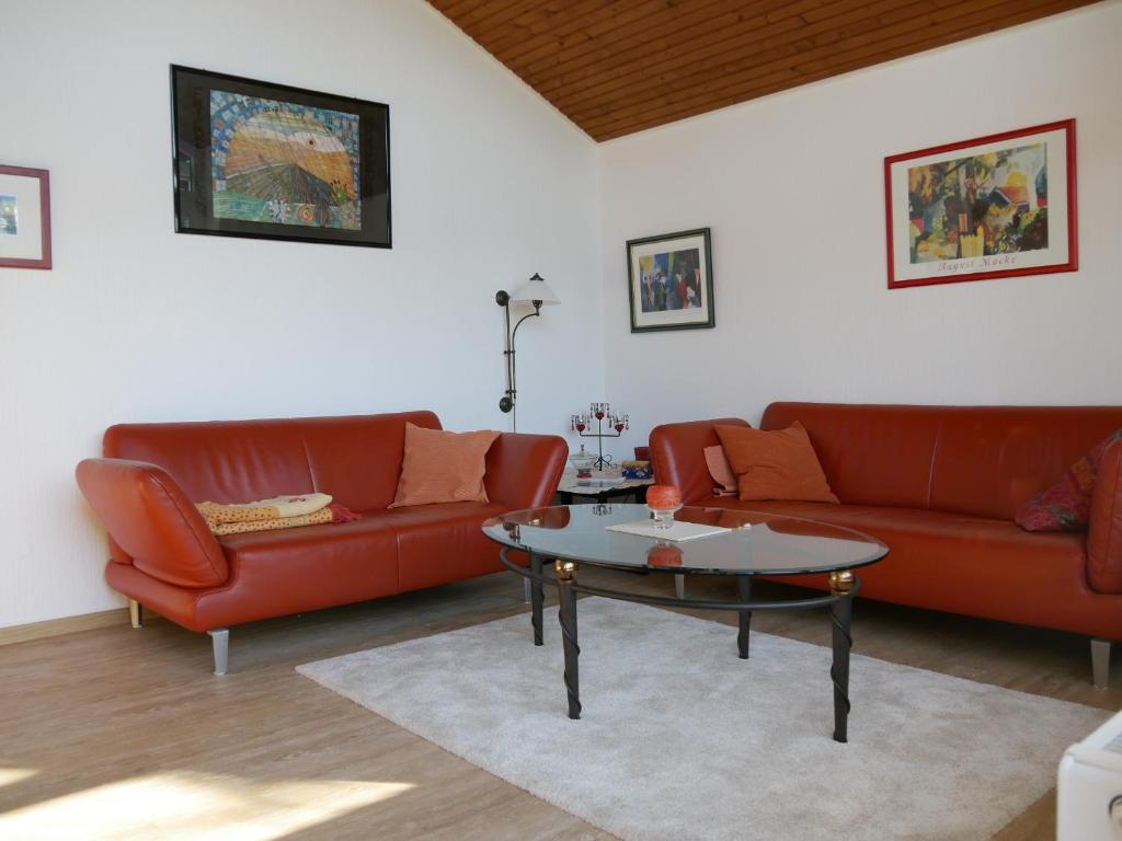 ein Wohnzimmer mit zwei roten Sofas und einem Tisch in der Unterkunft Ferienwohnung Haus Sonnenberg in Bremervörde