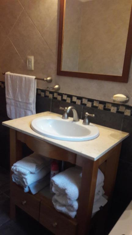 ein Badezimmer mit einem Waschbecken, einem Spiegel und Handtüchern in der Unterkunft Departamento Victoria Bariloche in San Carlos de Bariloche