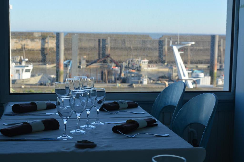 - une table avec des verres à vin et une fenêtre dans l'établissement Logis hôtel Le Terminus, à Bourcefranc