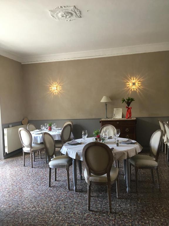 une salle à manger avec des tables, des chaises et des lumières sur le mur. dans l'établissement Les 2 grives - auberge restaurant, à Bras-dʼAsse