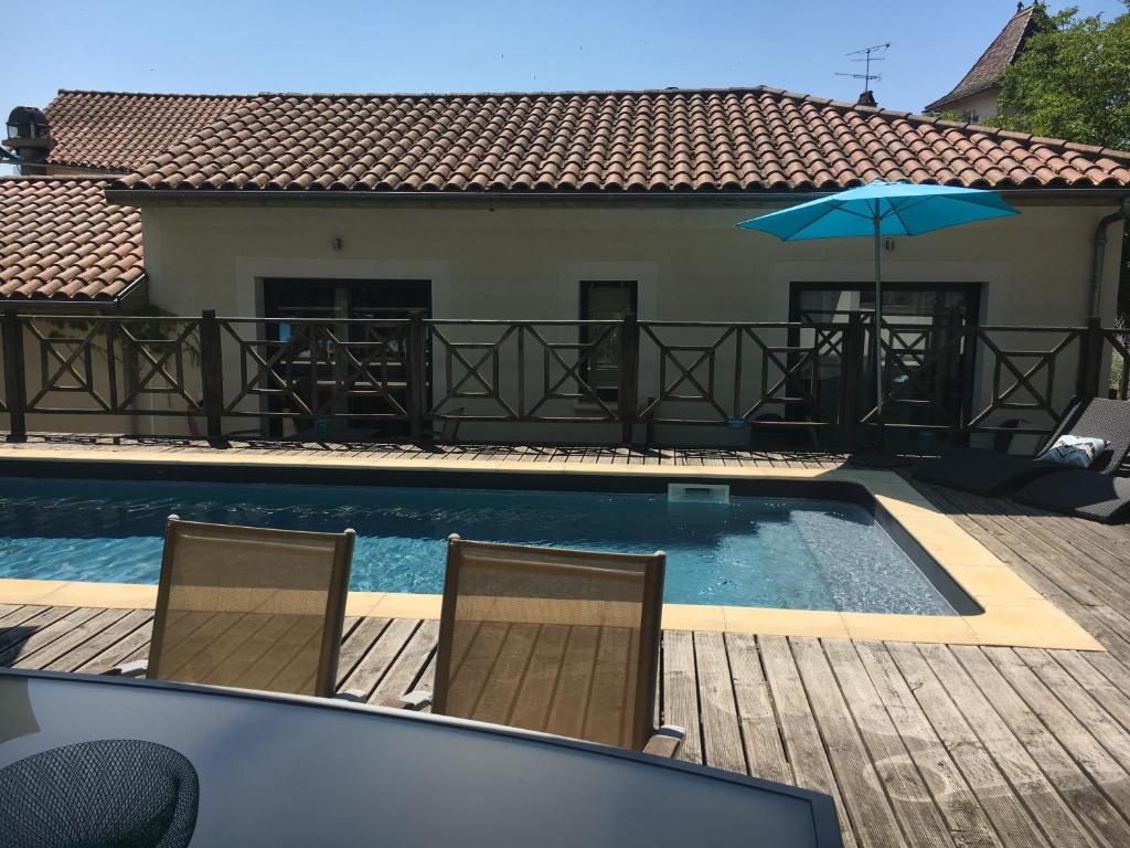 a swimming pool with two chairs and an umbrella at Le Vinois in Caillac