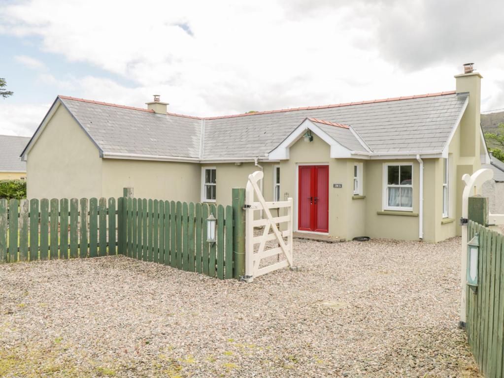 une maison avec une clôture verte et une porte rouge dans l'établissement Joe's Cottage, à Ardara