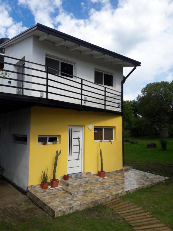 a yellow and white house with a balcony at Cabaña Los Pinos in Villa Icho Cruz