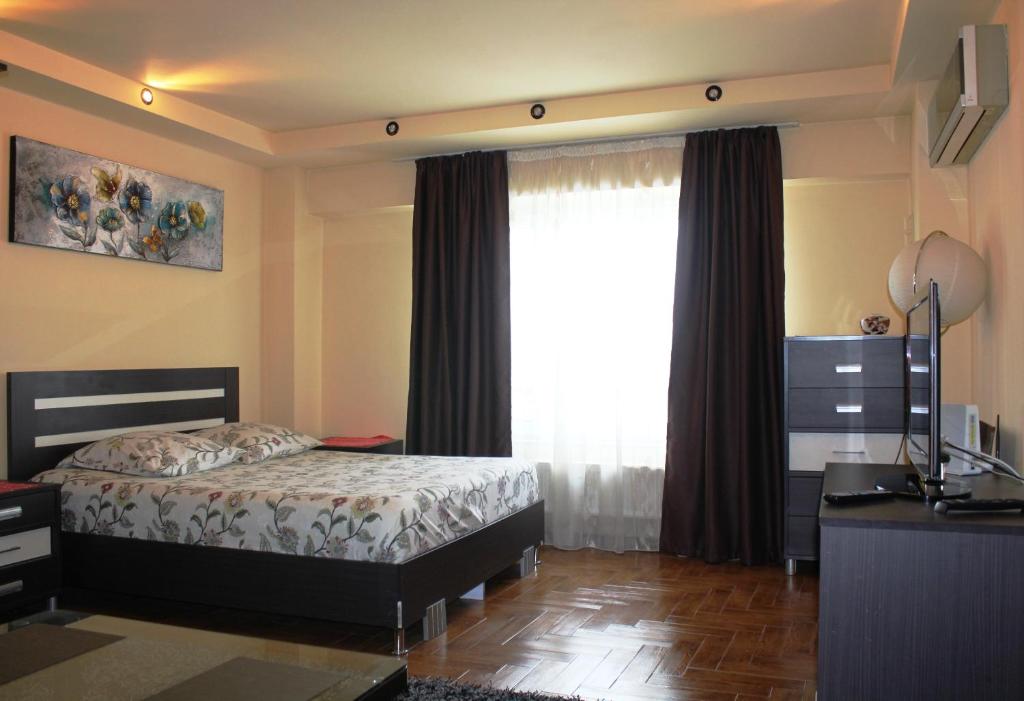 a bedroom with a bed and a window at City center Deluxe apartment in Bucharest