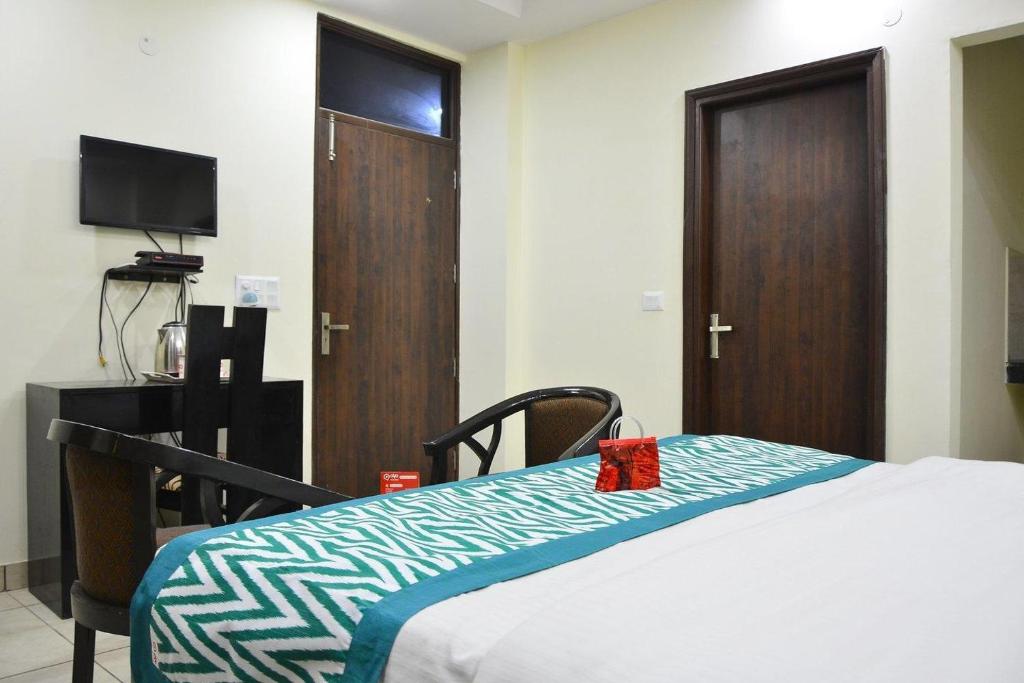 a bedroom with a bed and a tv and a door at Hotel Kundan Palace in New Delhi