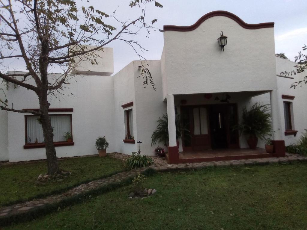 una casa blanca con un árbol en el patio en Hostal El Ensueño del Coquena en San Lorenzo