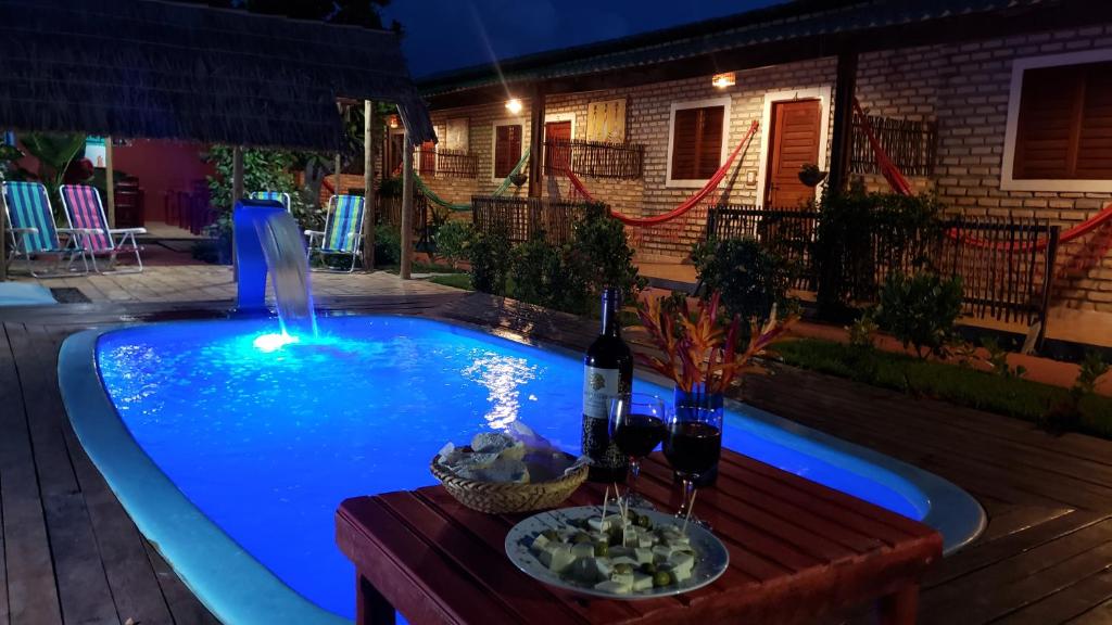 a swimming pool with a table and a bottle of wine at Pousada Brasil in São Miguel do Gostoso