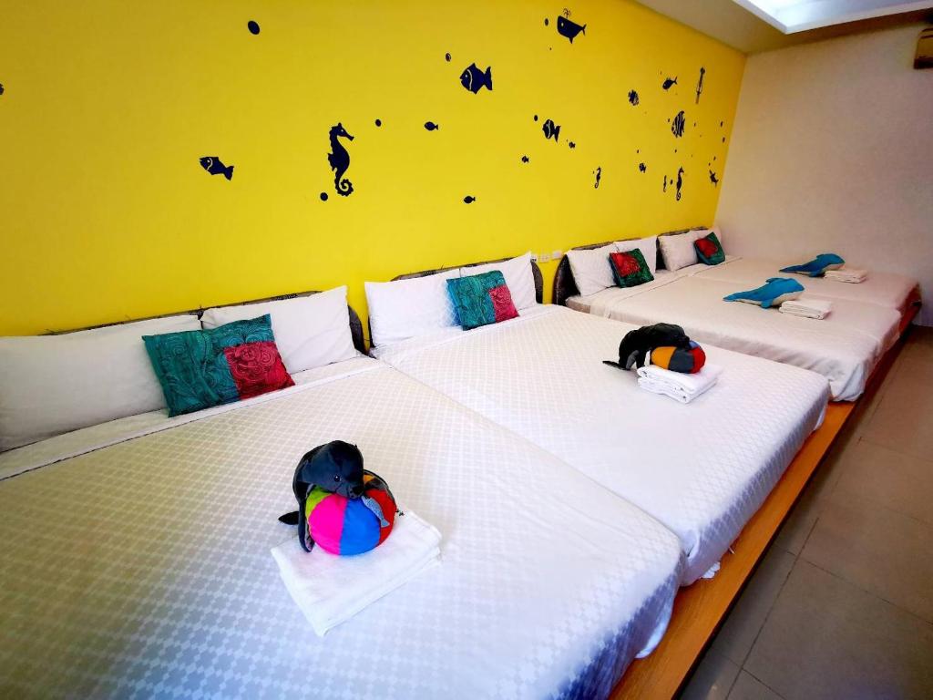 two beds in a room with a yellow wall at Nandian Homestay in Eluan