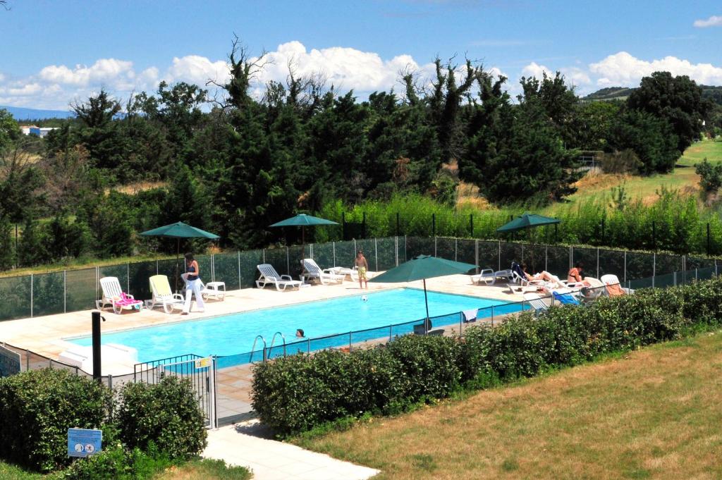 basen z ludźmi leżącymi wokół niego w obiekcie Residhotel Golf Grand Avignon w mieście Vedène