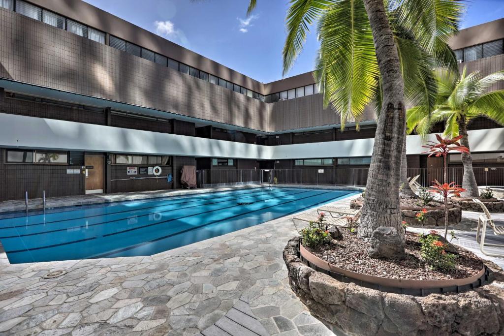 a swimming pool with a palm tree in front of a building at Downtown Honolulu Suite Near Ala Moana Beach! in Honolulu