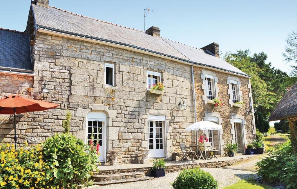 ein altes Steinhaus mit Sonnenschirm und Stühlen in der Unterkunft Crémoren Cottages in Scaër