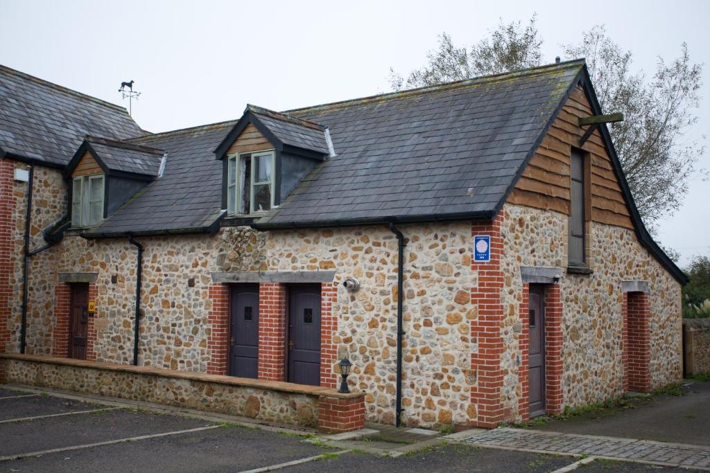 an old stone building with a black roof at Shave Cross Rooms in Bridport