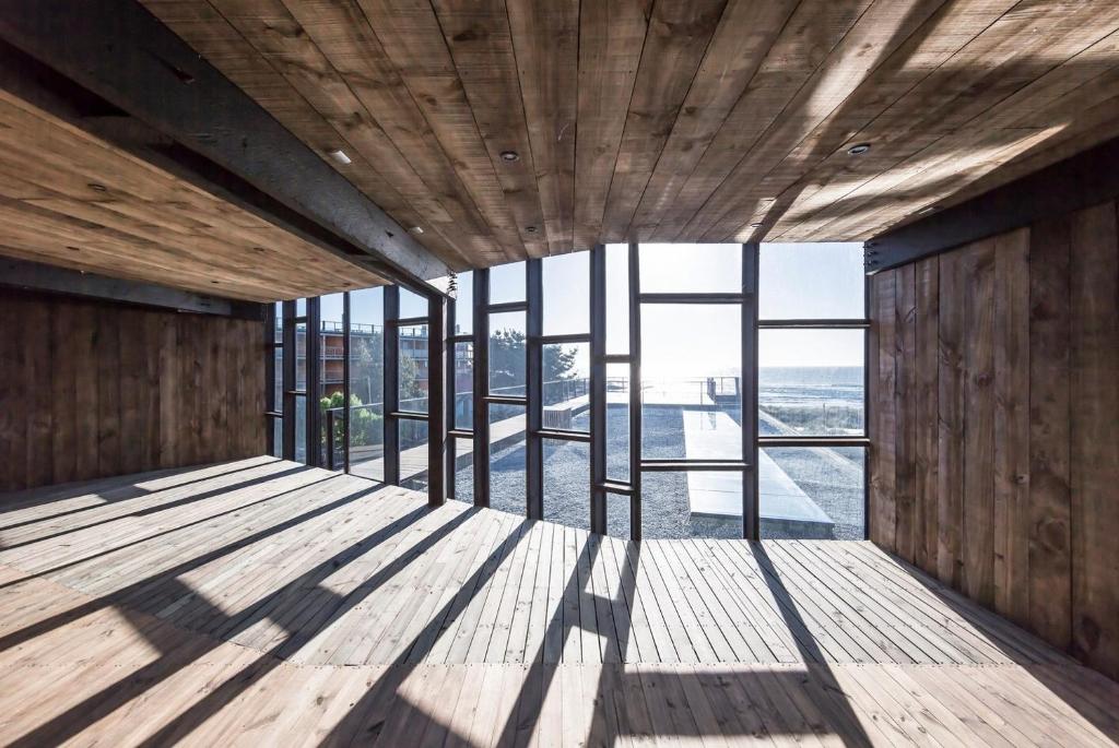 a room with wooden flooring and windows in a building at Hotel Punta Sirena in Curanipe