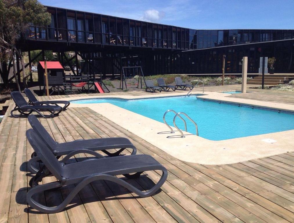 a swimming pool with a deck with a chair next to it at Hotel Punta Sirena in Curanipe