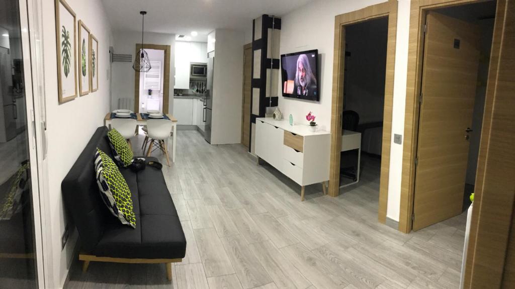 ein Wohnzimmer mit einem schwarzen Sofa und einem Schreibtisch in der Unterkunft Check-in 24H PLAZA ESPAÑA AMPLIO Centro 4 in Saragossa