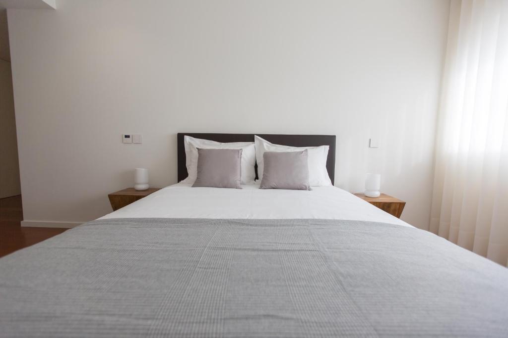 1 dormitorio con 1 cama grande con sábanas y almohadas blancas en Braga Luxury Residence 3854 en Braga