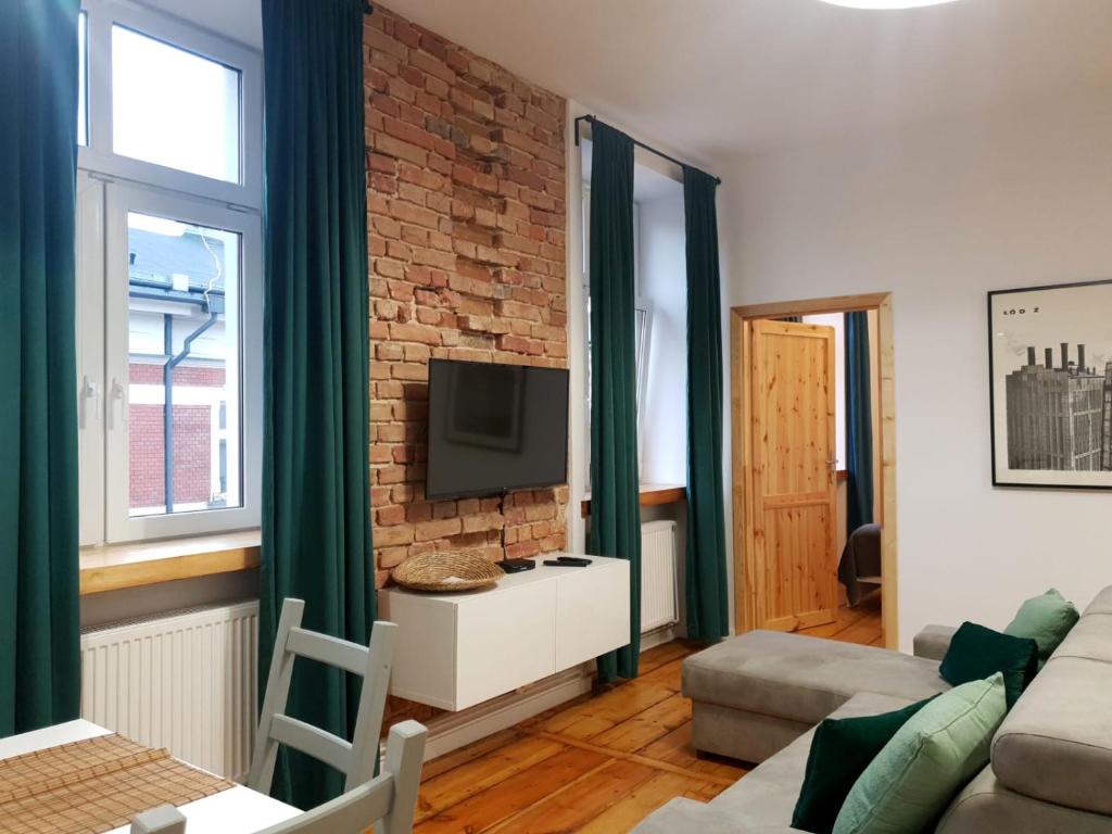 a living room with a brick wall and a tv at PanCake Apartament Piotrkowska free parking in Łódź