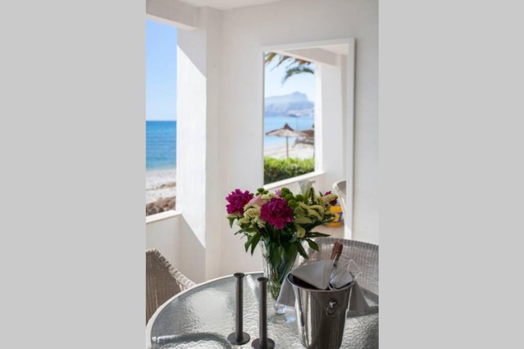 een wastafel met een vaas met bloemen voor een raam bij Oden 2 in Altea