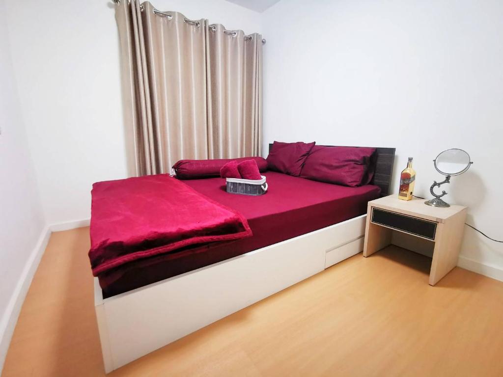 Un dormitorio con una cama con una manta roja. en Feel like Home, en Bangna