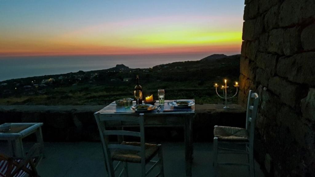 un tavolo e sedie con tramonto sullo sfondo di Kuddia Attalora a Pantelleria