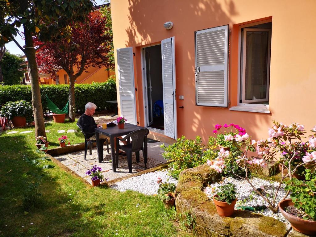 an older man sitting at a table outside of a house at A Due Passi Dal Mare B&B in Numana