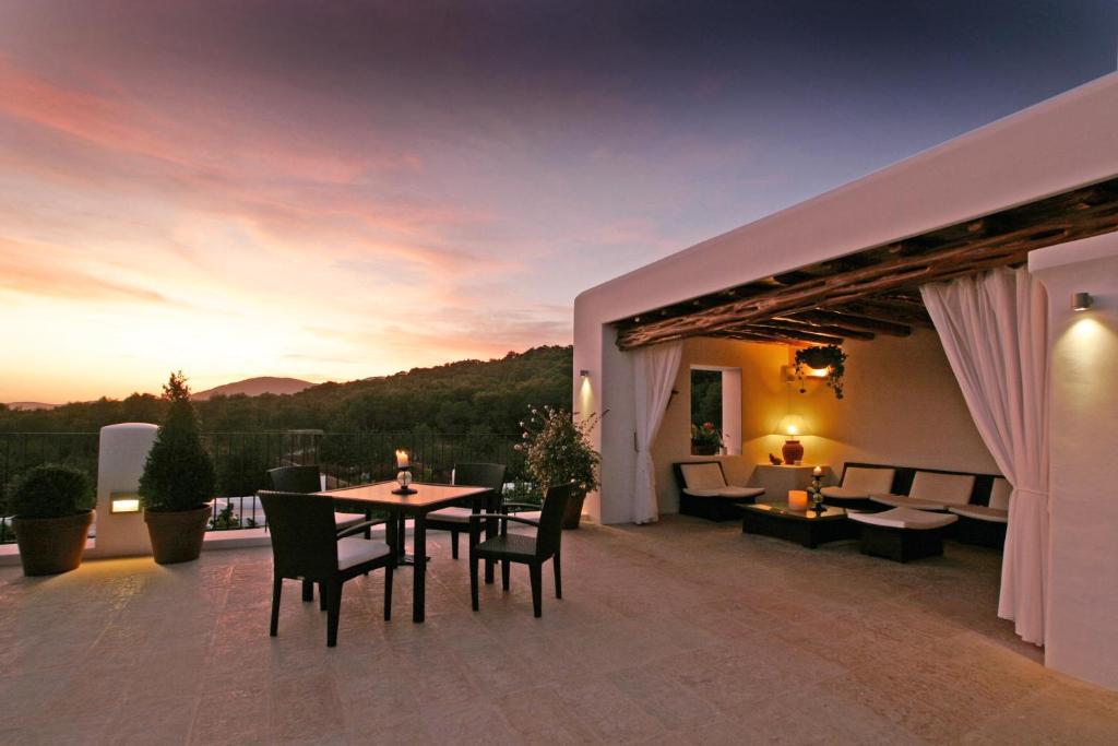 un patio con mesa y sillas al atardecer en Hotel Rural & Spa Can Curreu, en Sant Carles de Peralta