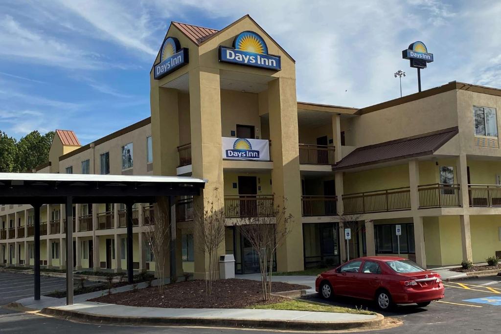 un hotel con un coche rojo estacionado frente a él en Days Inn by Wyndham Atlanta/Southlake/Morrow, en Morrow