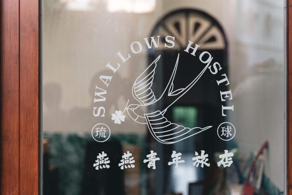 ein Fenster mit einem Schild mit einem Vogel drauf in der Unterkunft Swallows Hostel in Xiaoliuqiu