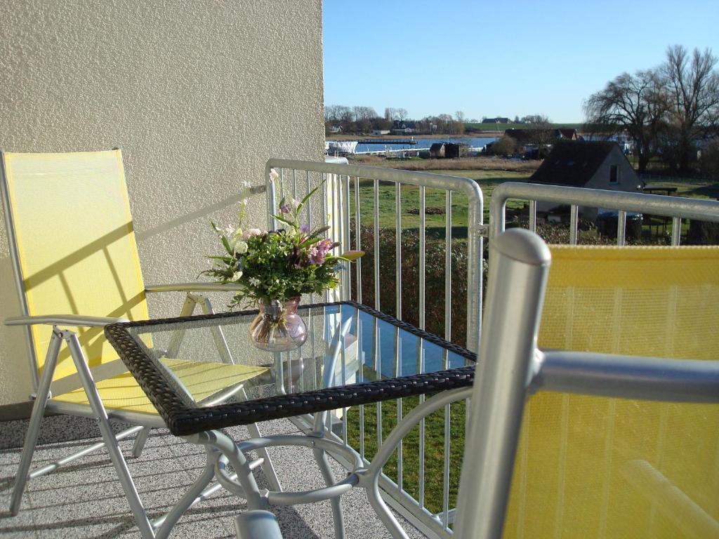 a glass table and chairs on a balcony with a vase of flowers at De Hafenkieker in Kirchdorf