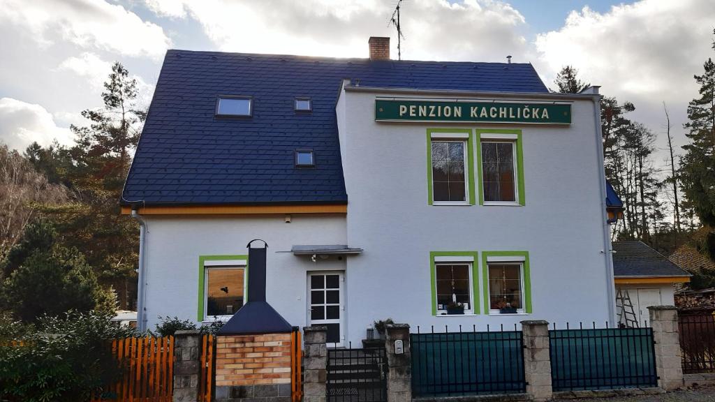 a white house with a sign on top of it at Pension Kachlicka in Skála