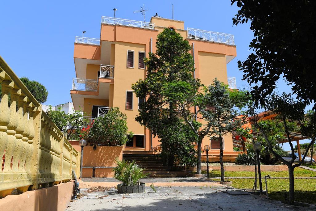 a yellow building with stairs and trees in front of it at B&B Il Canto Del Mare in Pulsano