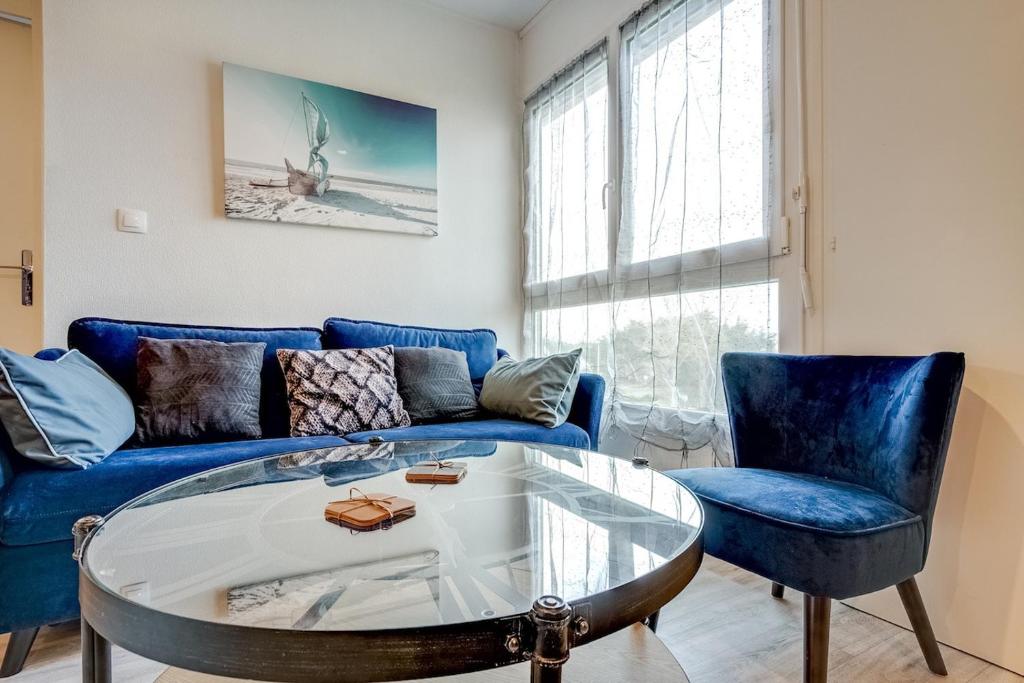 un salon avec un canapé bleu et une table en verre dans l'établissement Appart pour 4 - Plage à 250m à St Jean de Monts, à Saint-Jean-de-Monts